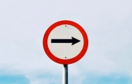 black arrow on white and red sign